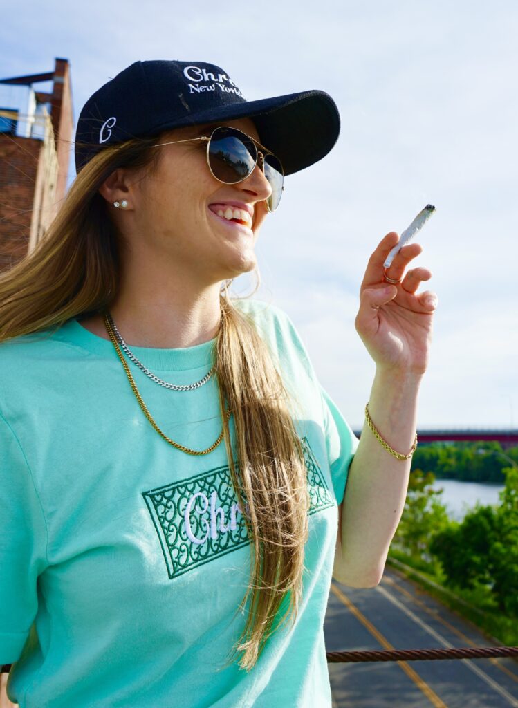 Smiling woman outdoors with cap and sunglasses.