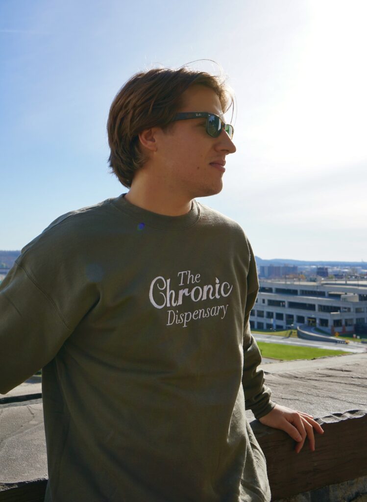 Person in sunglasses with 'The Chronic Dispensary' shirt.