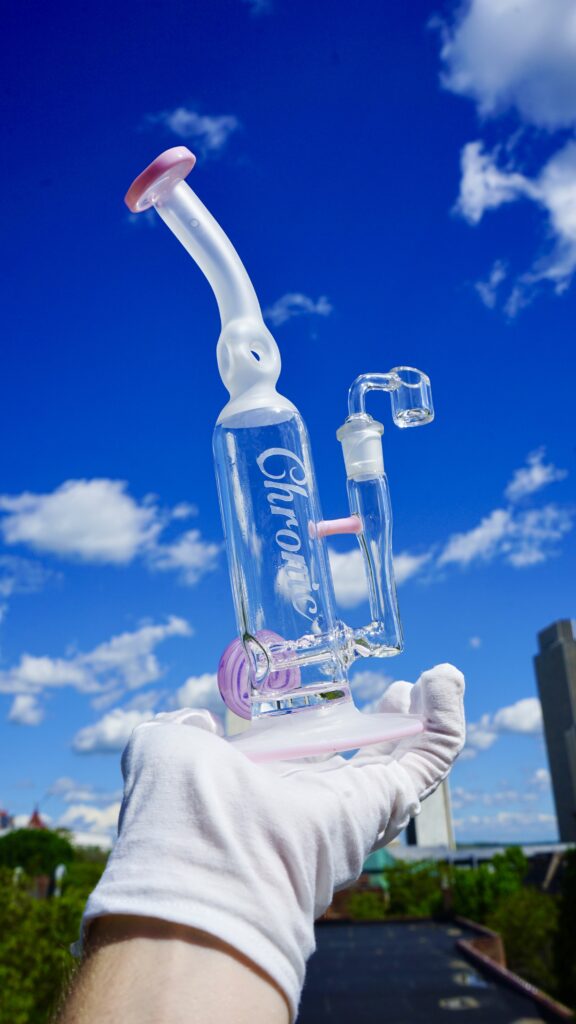 Hand holding a glass bong under blue sky